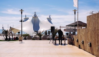 Person Standing Near Wooden Table on Concrete Pathway Under Blue and White Skies