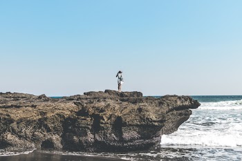 Person Standing On A Rock Beside Seashore