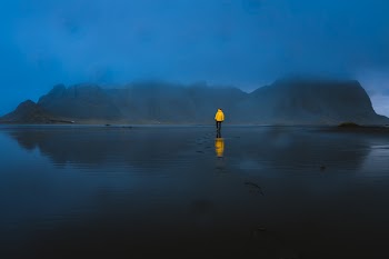Person Standing on Body of Water Near Island