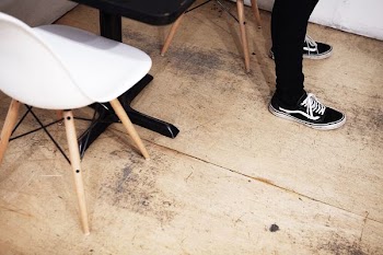 person standing on brown floor near table and chair