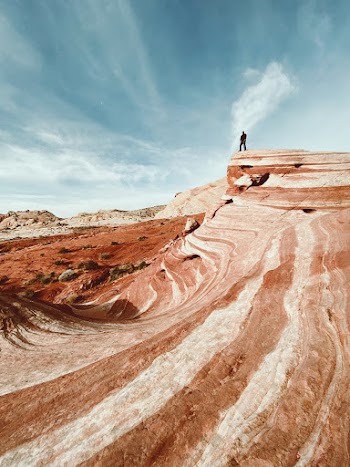 Person Standing on Brown Rock Formation Under Blue Sky