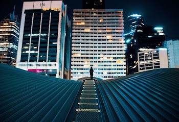 person standing on building roof with city buildings on background
