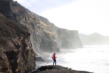 person standing on cliff near body of water during daytime
