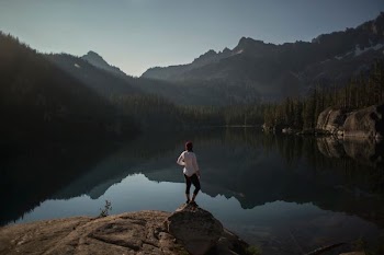 person standing on cliff near lake