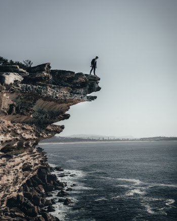 Person Standing on Cliff Near Seashore