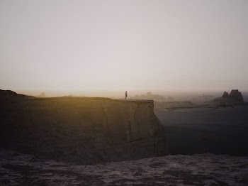person standing on cliff under white sky