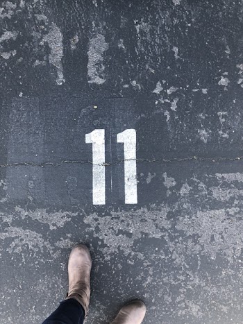 Person Standing On Concrete Floor With Number 11 Paint