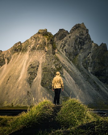 Person Standing on Grass Near Mountain
