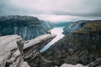 person standing on gray high-rise rock formation at daytime