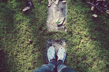 Person Standing on Gray Stone Surrounded by Green Grass during Daytime
