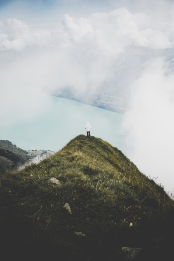Person Standing on Green Grass Mountain