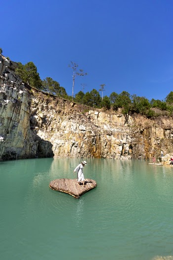 Person Standing on Heart Shaped Plank on Calm Water Near Mountain Cliff