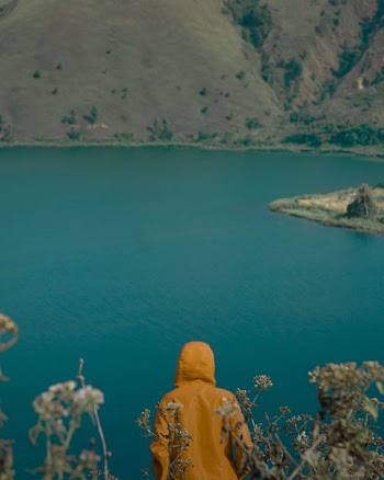 person standing on high grounds looking at calm waters