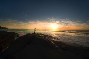 person standing on mountain facing sun at golden hour