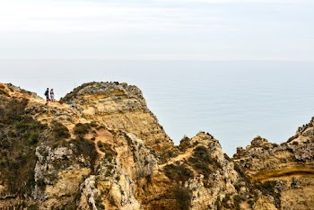 Person Standing on Mountain Overlooking Body of Water