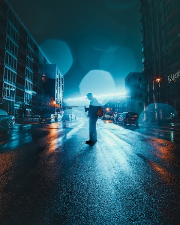 Person Standing on Road Between Buildings