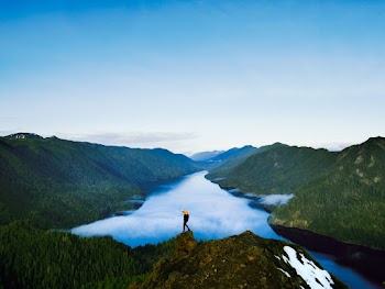 Person Standing on Rock Formation Near Lake