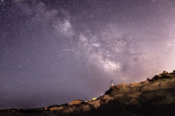 person standing on rock formation under starry sky