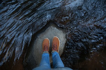 Person Standing on Rock in Between Running Water