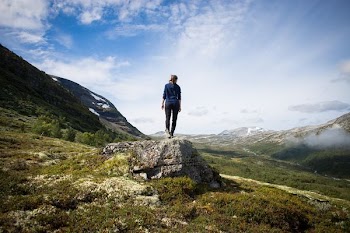 person standing on rock looking at mountain