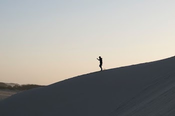 person standing on sand under white sky during daytime