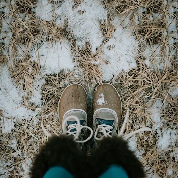 person standing on sand wearing brown duck boots
