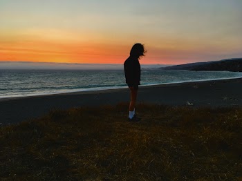 Person Standing on Seashore during Sunset