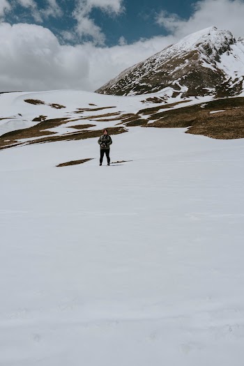 Person Standing on Snow Covered Mountain