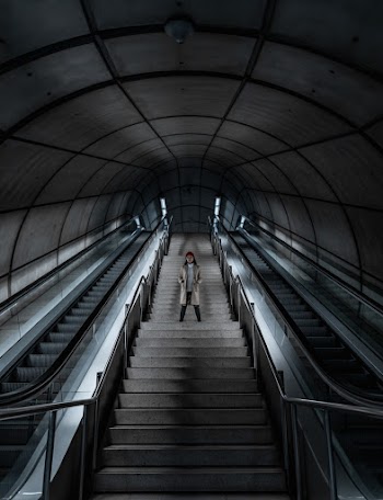 Person Standing on Stairway Beside Escalators