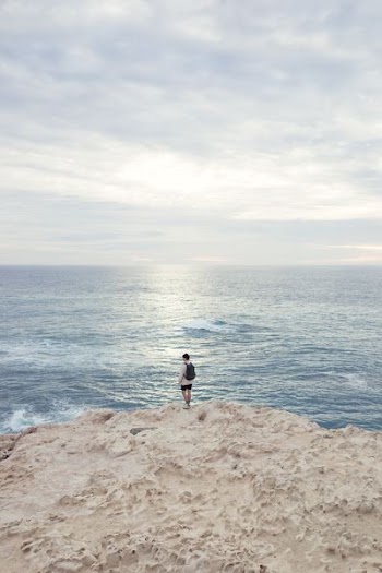 person standing on the edge of the cliff near ocean