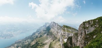 person standing on top of mountain overlooking body of water