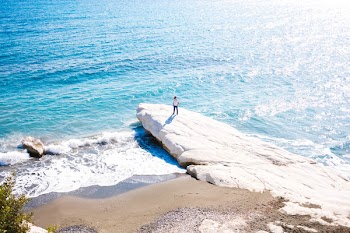 Person Standing on White Boulder Near Body of Water