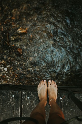 Person Standing on Wooden Bridge Near Creek
