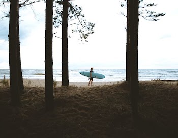person standing while carrying blue surfboard near sea during daytime