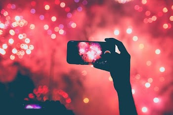 person taking a photo of fireworks using smartphoen