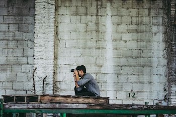 person taking photo near white concrete wall