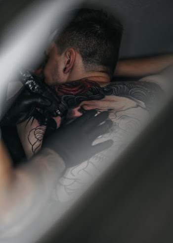 Person Tattooing Man's Back