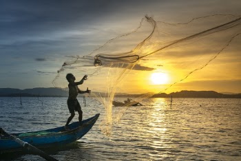 Person Throwing Fish Net While Standing on Boat