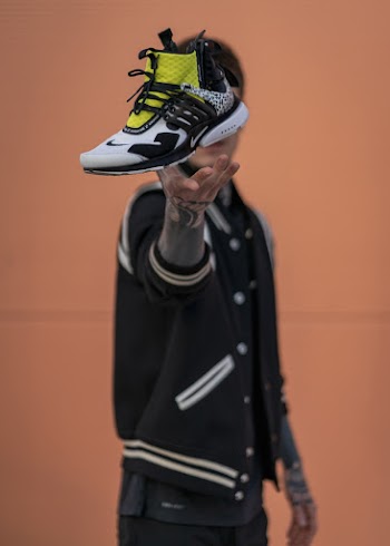 Person Throwing White, Black, and Green Nike Air Presto Shoe