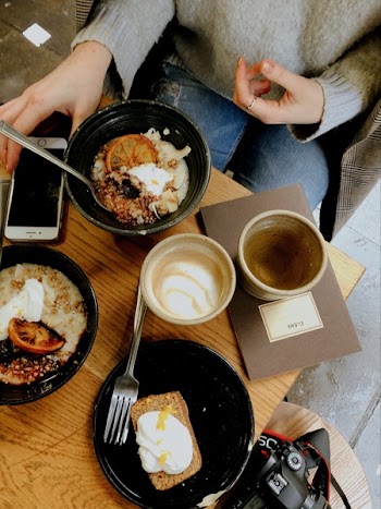 Person Touching Turned-off Silver Iphone 6 on Top of Table Beside Round Black Ceramic Bowl Filled With Food