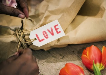 Person Tying Knot on Brown Paper Bag With Love Tag