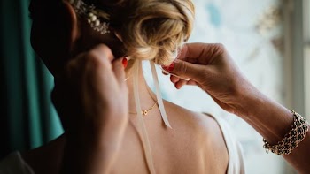 person tying white ribbon on blonde-haired woman