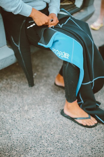 Person Unzipping Black and Teal Scuba Suit