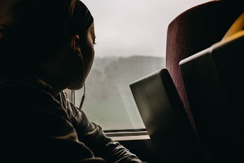 person using earphones looking through window