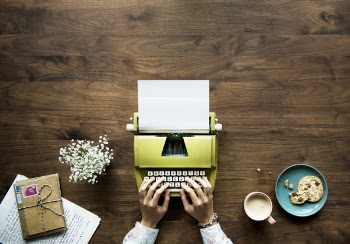 Person Using Green Typewriter On Brown Wooden Surface