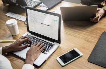 Person Using Macbook Pro Beside Iphone