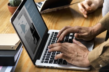 Person Using Macbook Pro on Brown Table