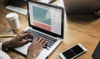 Person Using Macbook Pro on Brown Wooden Table