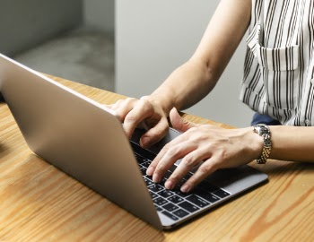 Person Using Macbook Pro on Brown Wooden Table