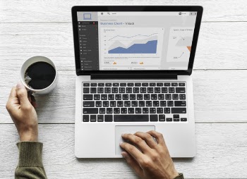 Person Using Macbook Pro While Holding Mug